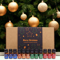 Set Delicias Festivas abierto con doce frascos de aceite aromático delante de un árbol de Navidad con bolas rojas y doradas