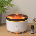 Difusor de aromas blanco con bruma iluminada en tono naranja que imita una llama, junto a un frasco de aceite esencial
